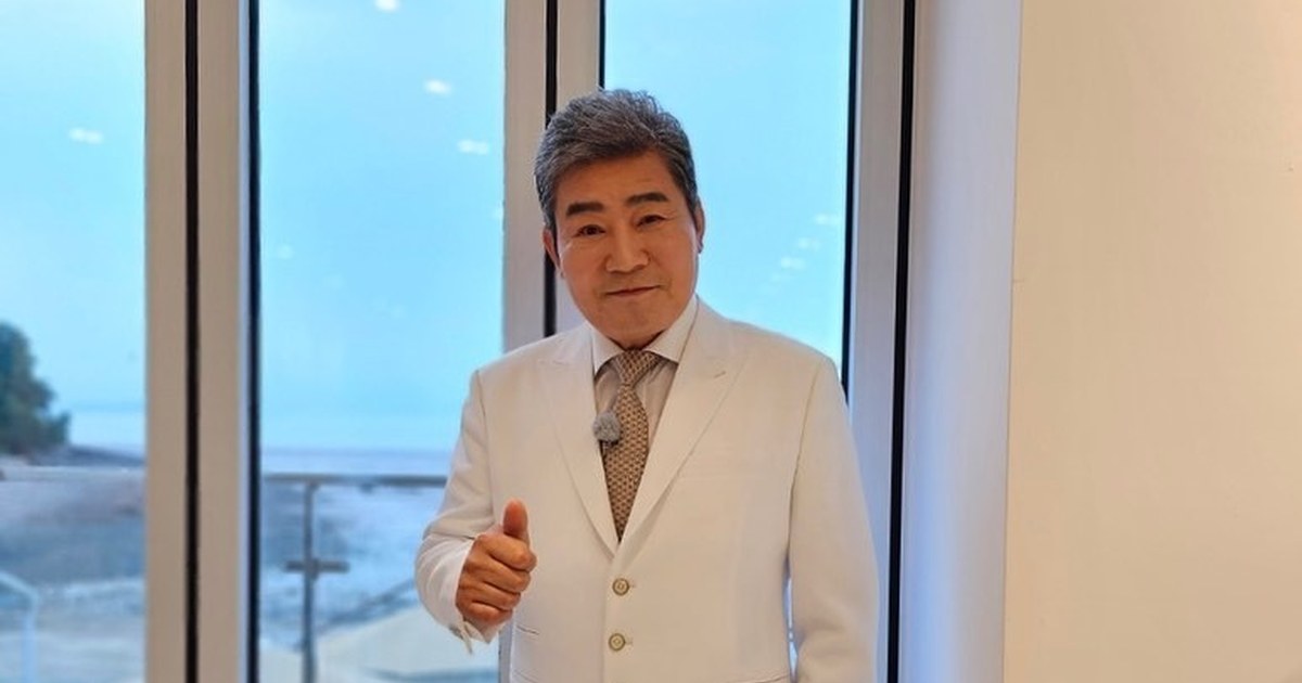 진성이 파란색 체크 재킷을 입고 인터뷰하며 웃는 모습