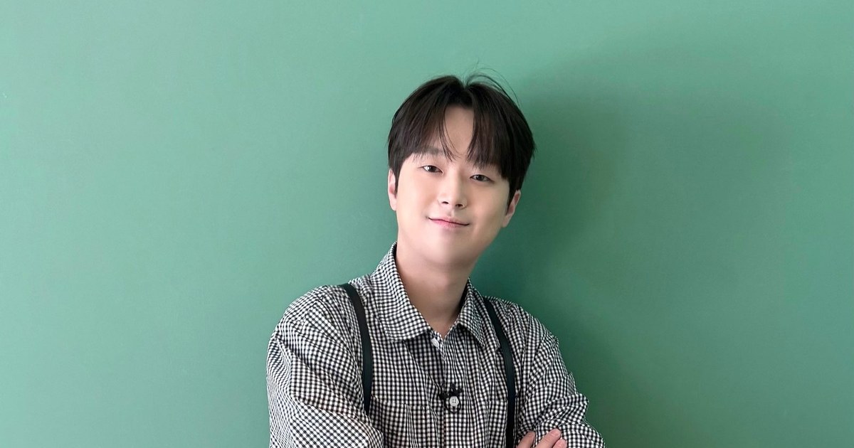 체크무늬 셔츠 차림으로 팔짱을 끼고 미소 짓는 이찬원의 상반신 사진