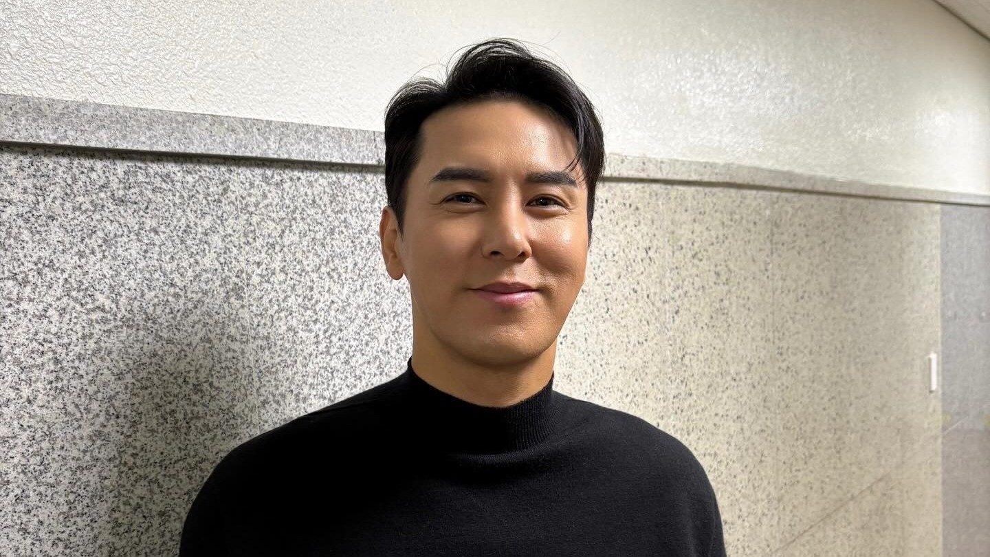 장민호가 콘서트 현장 대기실에서 검은색 스웨터를 입고 웃는 모습