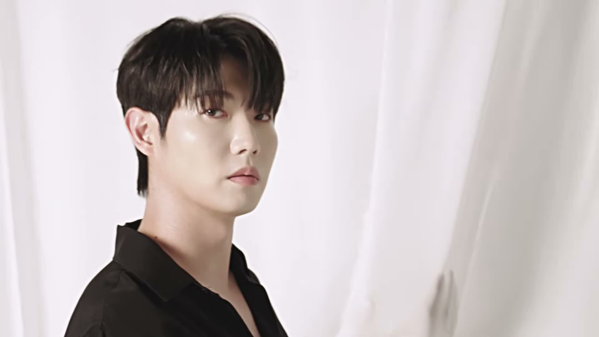 흰 커튼 앞에서 검은 셔츠를 입고 카메라를 바라보는 손태진