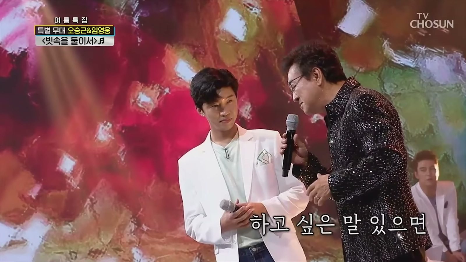 임영웅이 흰 재킷 차림으로 마이크를 들고 오승근과 마주 선 모습