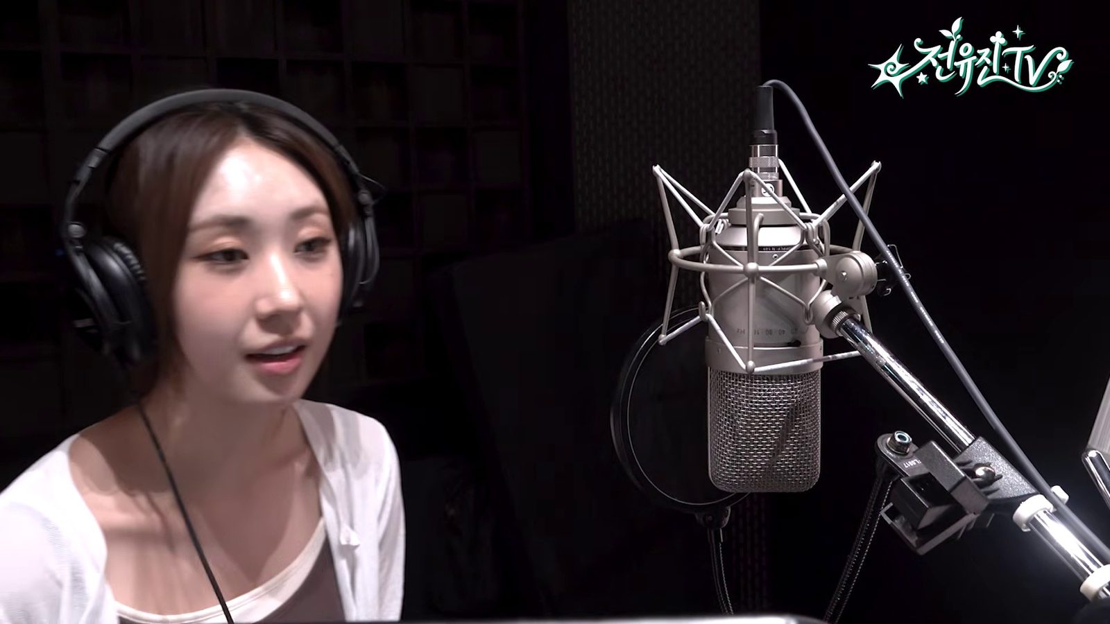 녹음실 마이크 앞에서 헤드폰을 쓰고 말하는 전유진
