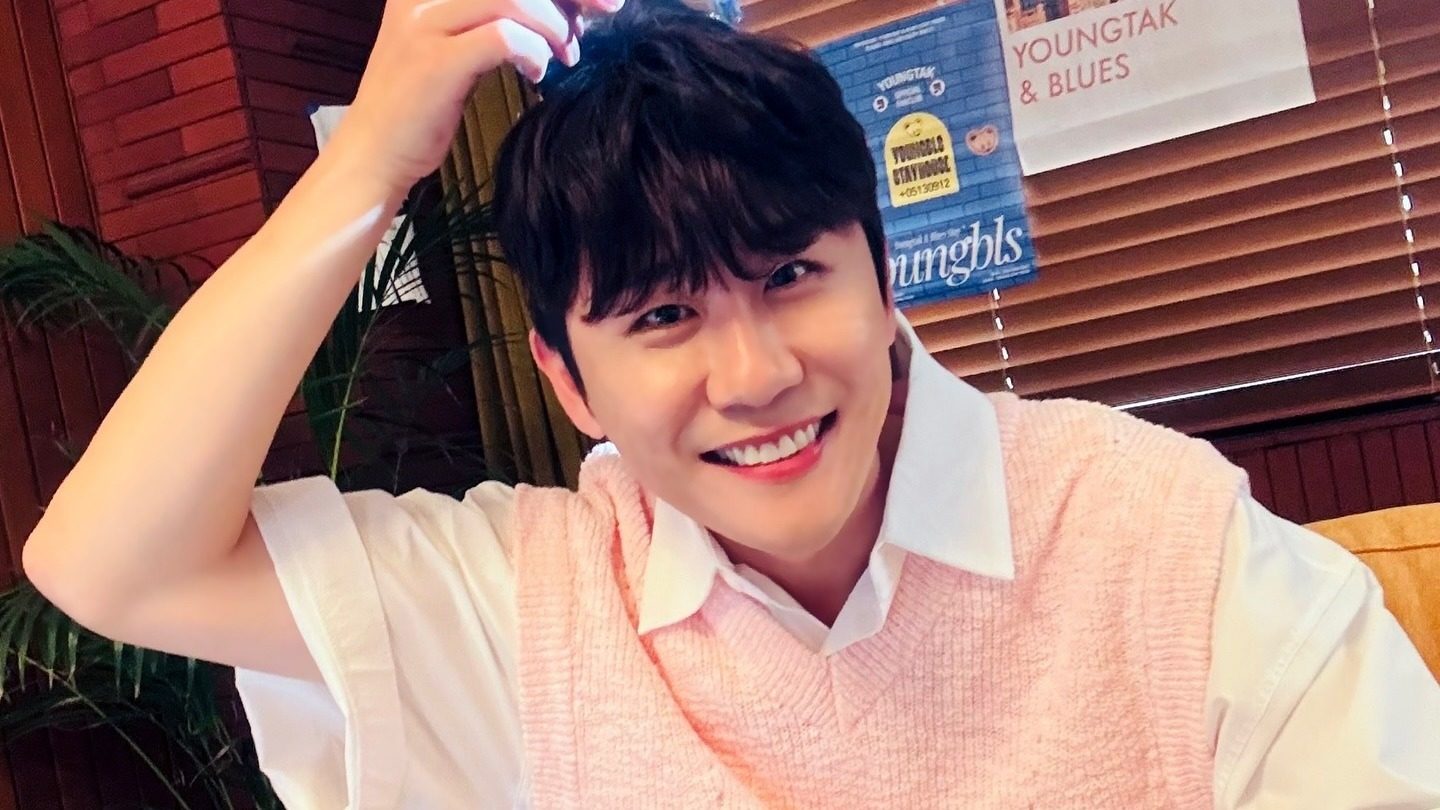 분홍색 니트 조끼 차림으로 한 손을 머리에 얹고 활짝 웃는 영탁