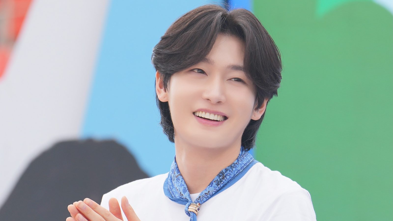 파란 스카프에 흰 티셔츠 차림으로 박수를 치며 환하게 웃는 김용빈