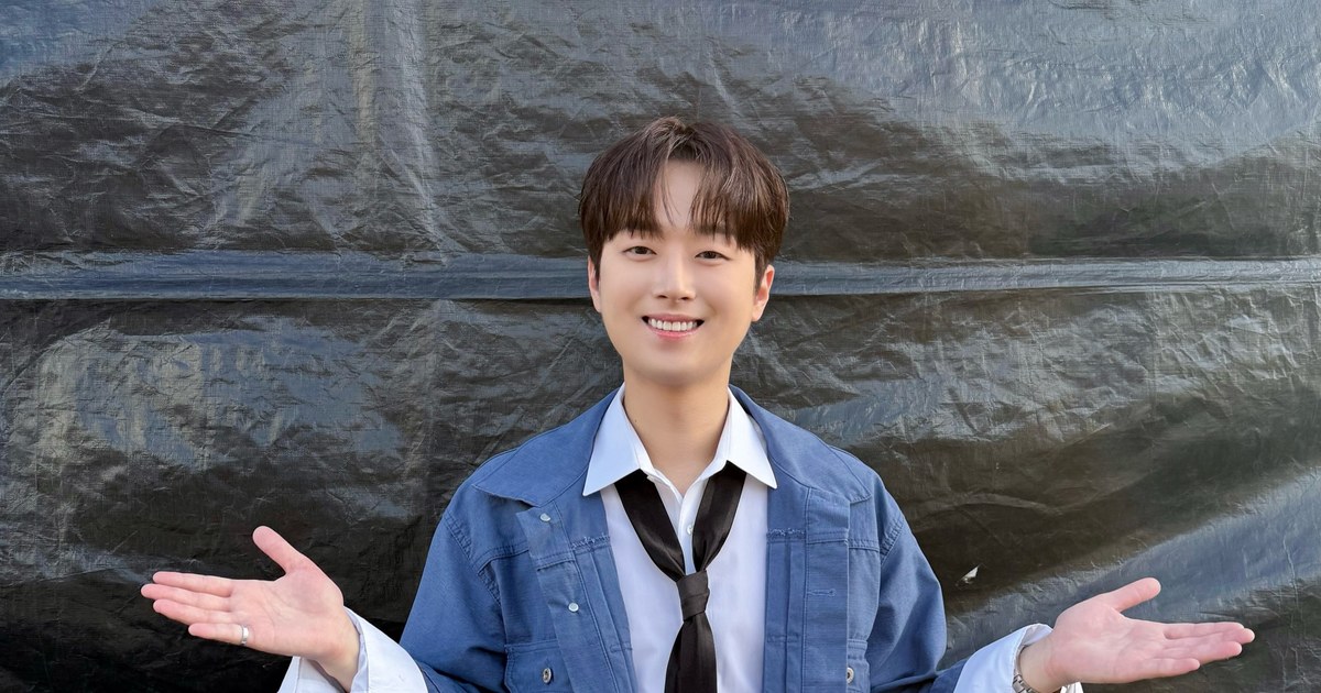 청색 데님 재킷에 넥타이 차림으로 두 팔을 벌리고 웃는 이찬원
