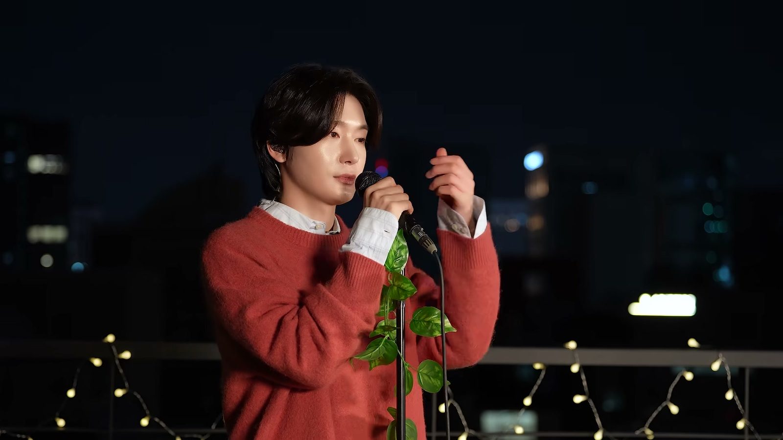 밤 옥상 무대에서 붉은 스웨터 차림의 김용빈이 마이크를 잡고 노래하는 모습