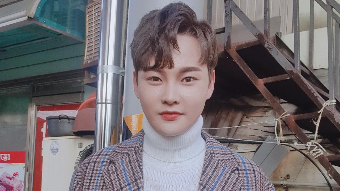 흰 터틀넥에 체크무늬 코트를 입고 정면을 바라보는 박서진