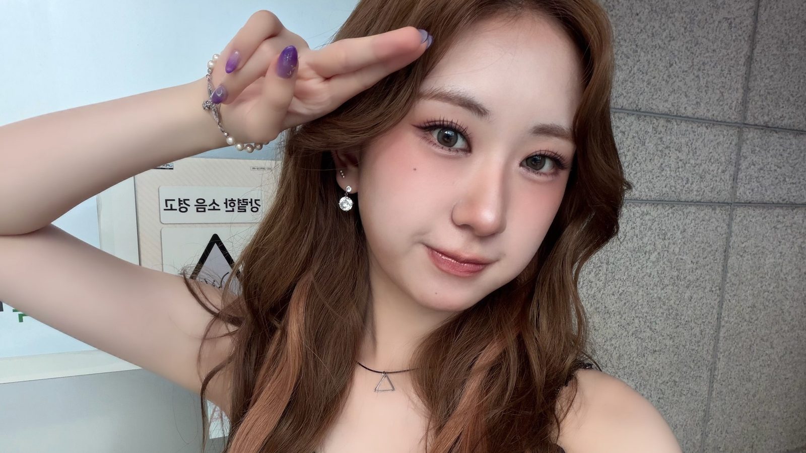 갈색 웨이브 머리의 전유진이 손으로 이마 옆에 브이 모양 경례를 하며 웃는 셀카