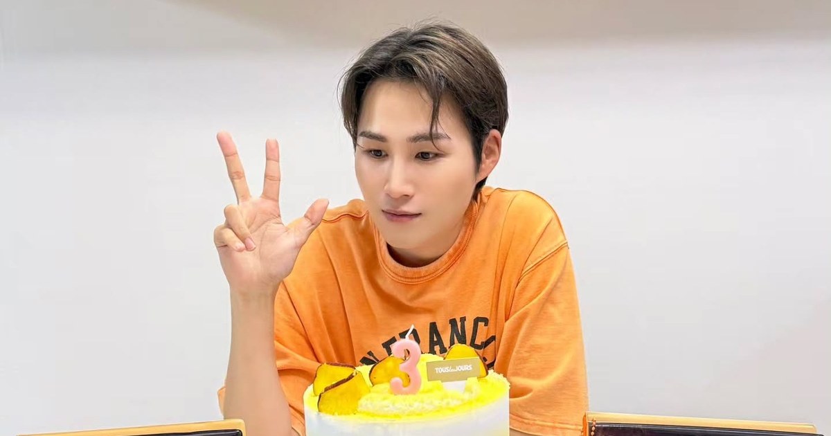 주황색 티셔츠 차림으로 브이를 하며 케이크를 바라보는 김희재